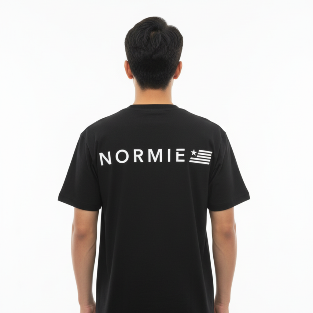 Person wearing a black t-shirt with 'NORMIE' printed on the back against a white background