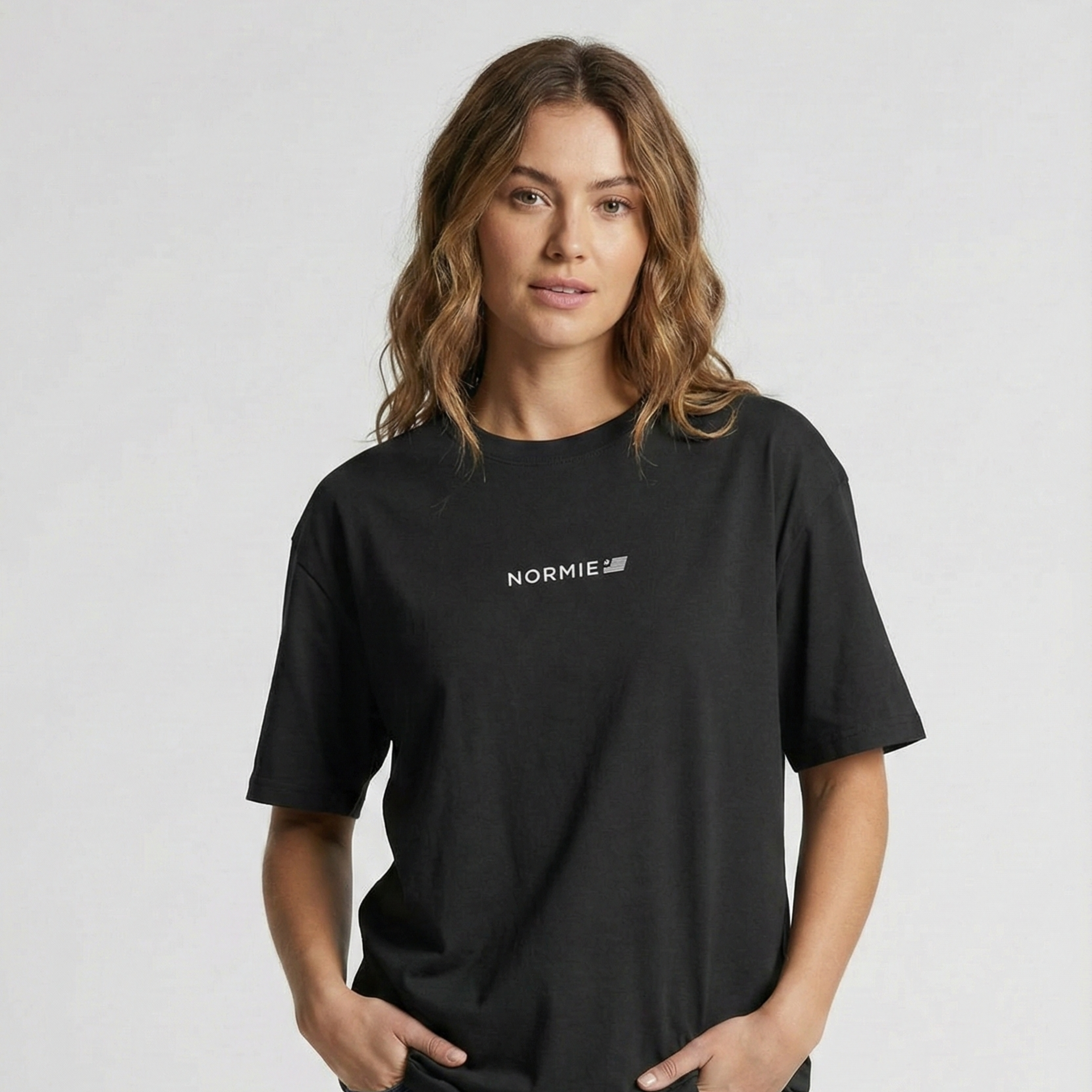 Woman wearing a black t-shirt with 'NORMIE' logo on a light gray background