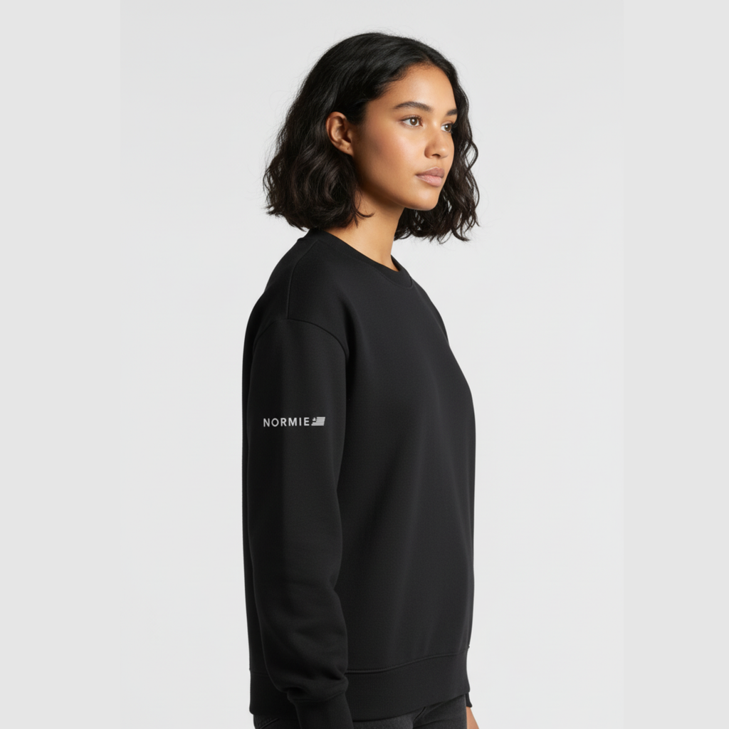 Person wearing a black sweatshirt with 'NORMIE' branding on a light gray background
