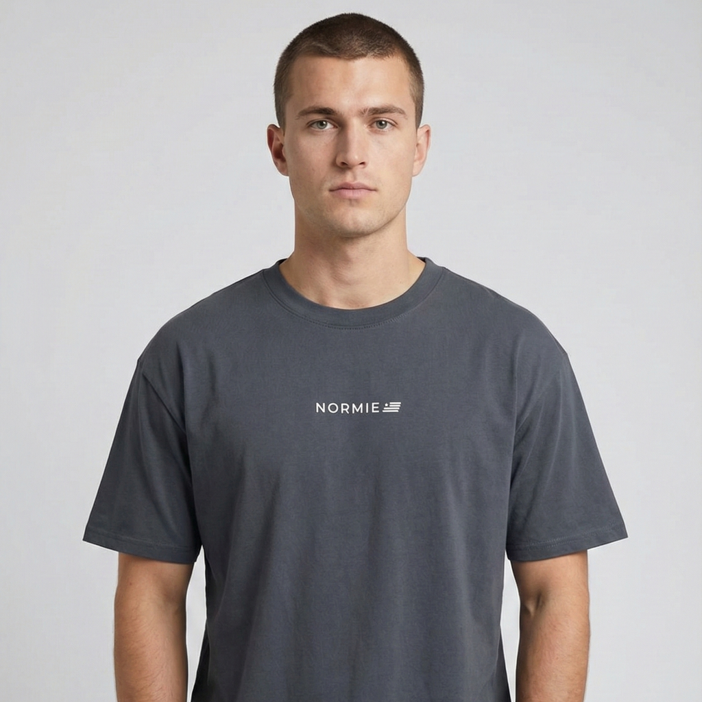 Man wearing a indigo blue t-shirt with 'Normie' logo on a light gray background