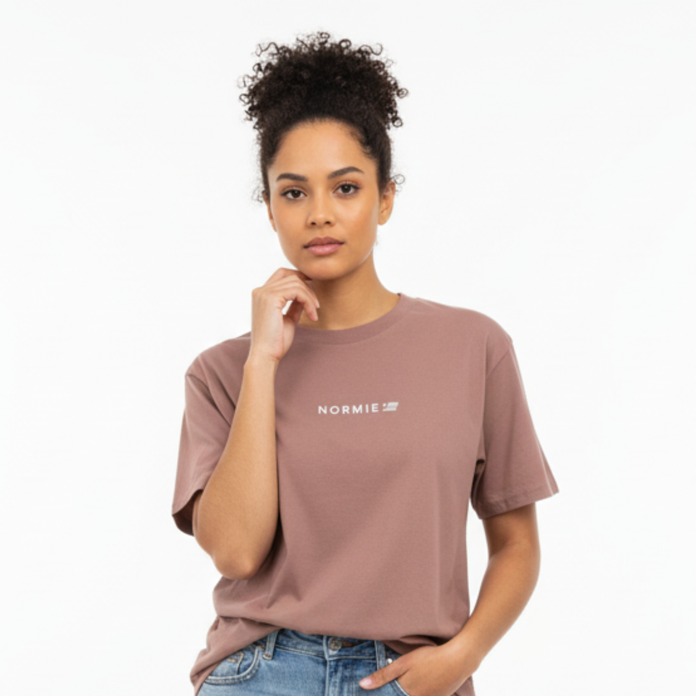 Woman wearing a mauve t-shirt with text and light blue jeans on a white background